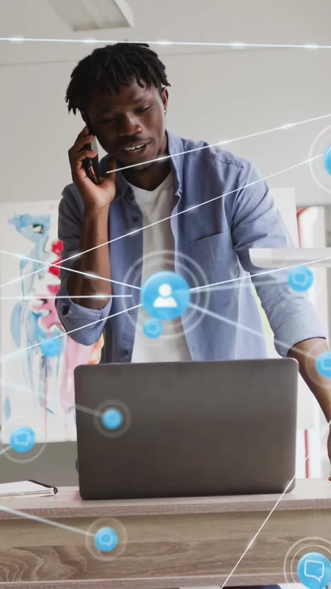 Vertical video: Man speaking on phone, blue network nodes expanding from laptop Stock Footage 334317222