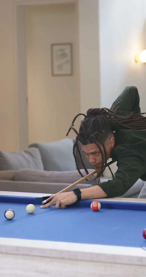 Vertical video: Man spotting balls at pool table aligning cue and executing shot Stock Footage 345129326