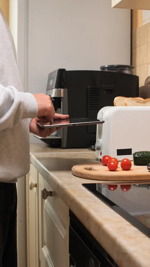Vertical video man standing in kitchen interacting with a digital tablet while 動画素材 343166200