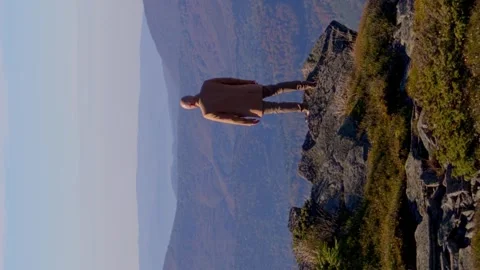 Vertical video. A man stands on the edge of a cliff and looks into the distance Video stock 246328995