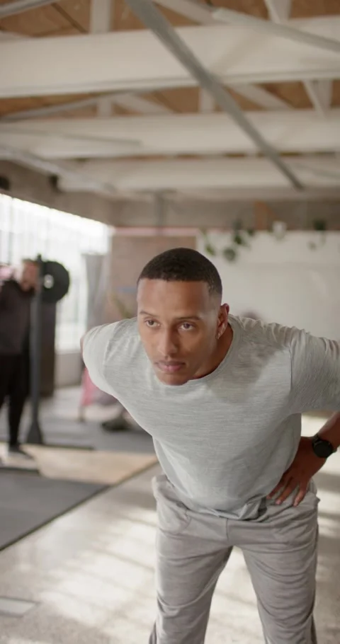 Vertical video: Man starting hands on hips, leaning and reaching back in loft Stock Footage 337259406