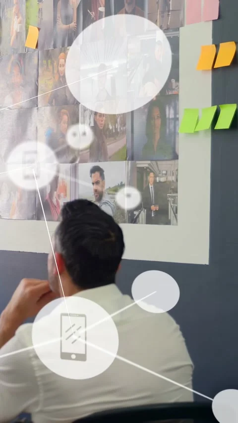 Vertical video: Man studying grid, peer adding notes causing icons over Stock Footage 333006263