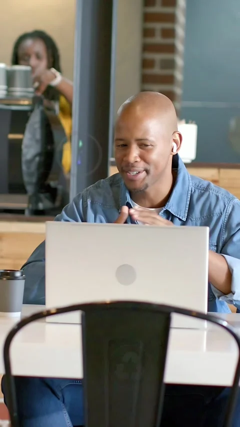 Vertical video: Man talking eco data above laptop in cafe, causing animated Stockbeeldmateriaal 333464834