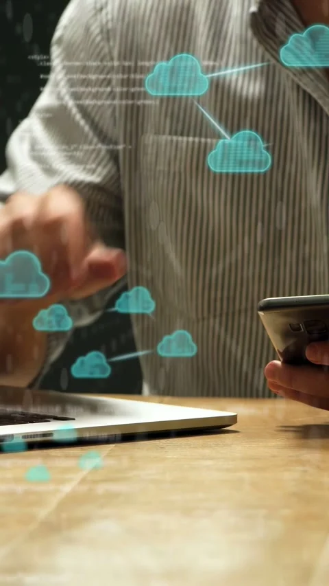 Vertical video: Man tapping cell at desk starting cloud icons and code overlay Stock Footage 334694952