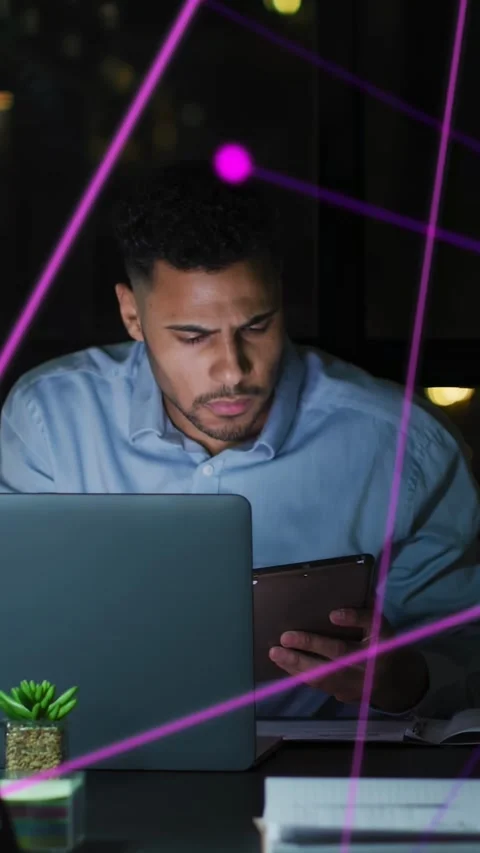 Vertical video: Man tapping tablet, checking laptop for data, purple nodes Stock Footage 333721133