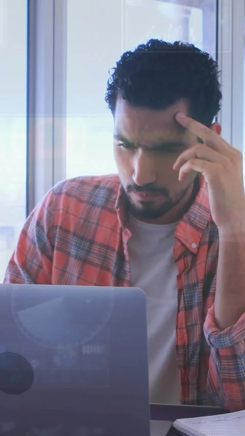 Vertical video: Man typing at laptop by window, causing code overlays on glass Stock Footage 333835834