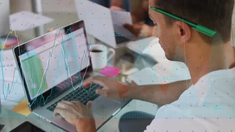 Vertical video: Man typing on laptop at table, causing live graphs over sheet Stock Footage 334036903