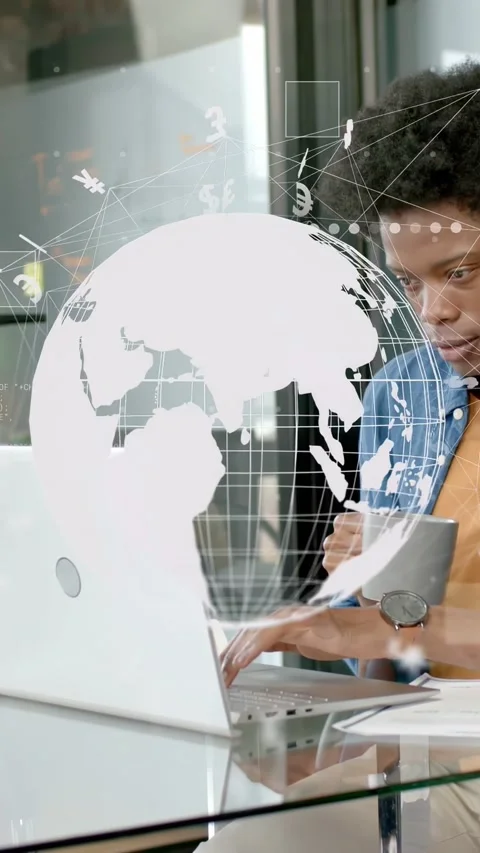 Vertical video: Man typing on laptop at glass desk, making globe spin with money Stock Footage 334917155