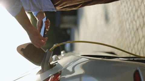 Vertical video of man unplugging electric car cable. Guy stopping charging using Stock Footage 200966457
