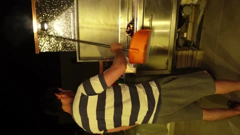 Vertical video of a man using a dustpan to air out a grill so that it lights up Stock Footage 172269456