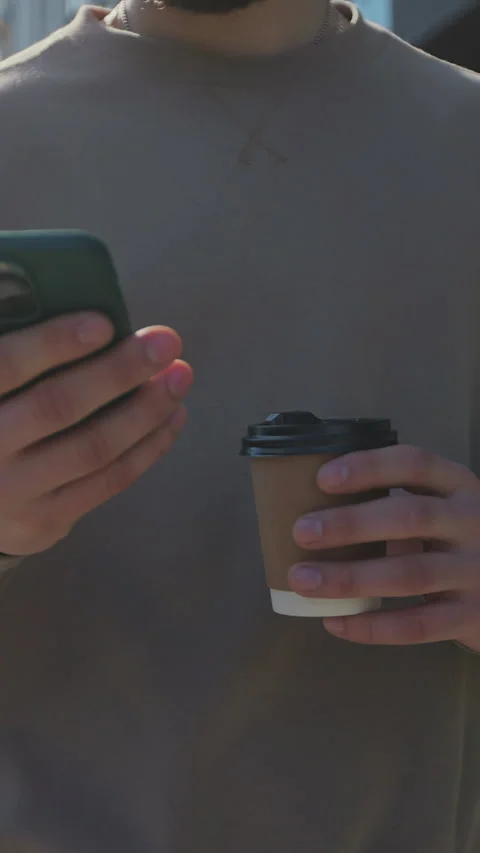 Vertical video. Man using a smartphone and holding takeaway coffee Stock-Footage 344108674