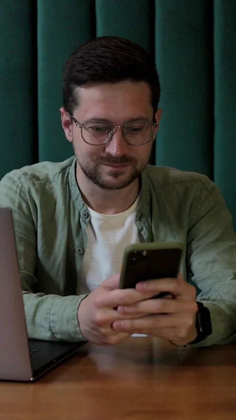 Vertical video. Man using smartphone and laptop in coffee shop. Stock Footage 345236986