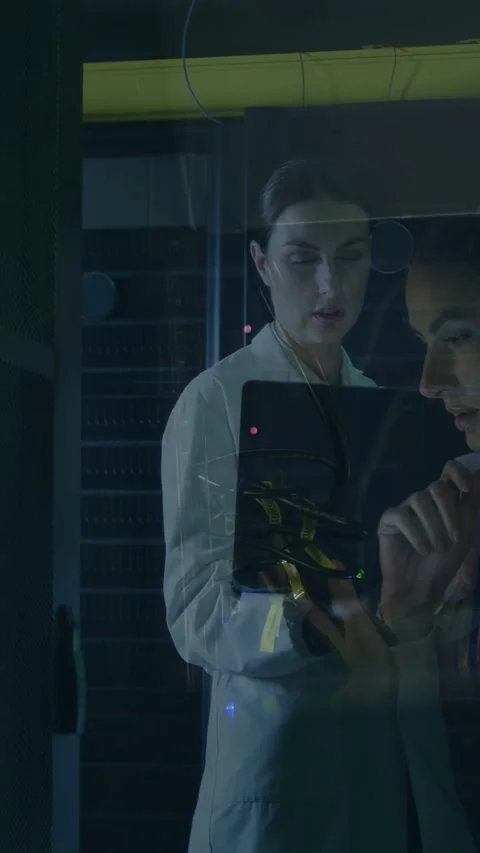 Vertical video: Man using unit behind glass, woman watching, red LED drawing Stock Footage 332985159