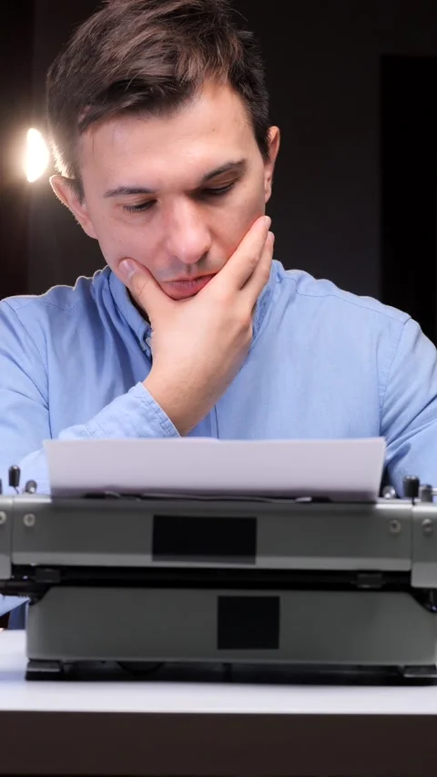 Vertical video Man at vintage typewriter pauses in deep thought, finding Stock Footage 321621747