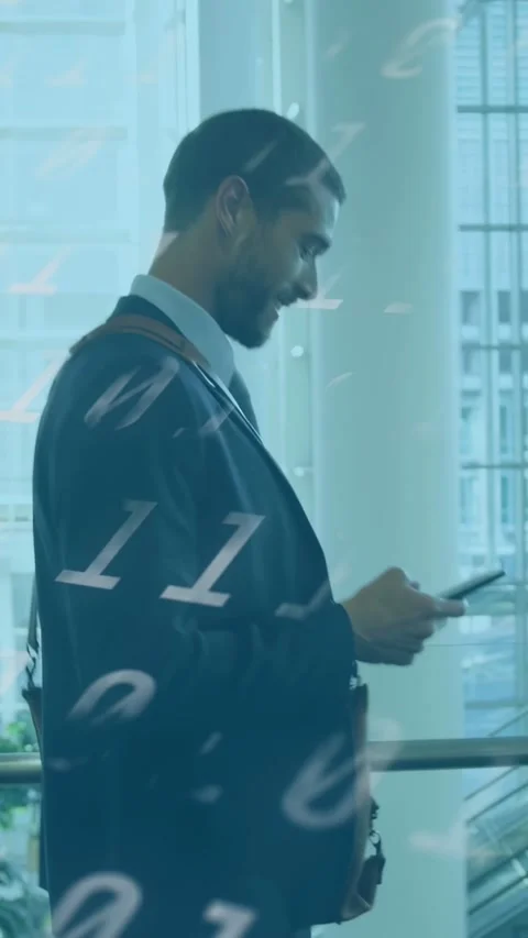 Vertical video: Man walking atrium reading phone causing binary code overlay Stock Footage 333556750