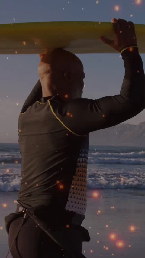 Vertical video: Man walking to sea holding yellow board above head, sparks 스톡 동영상 334604613