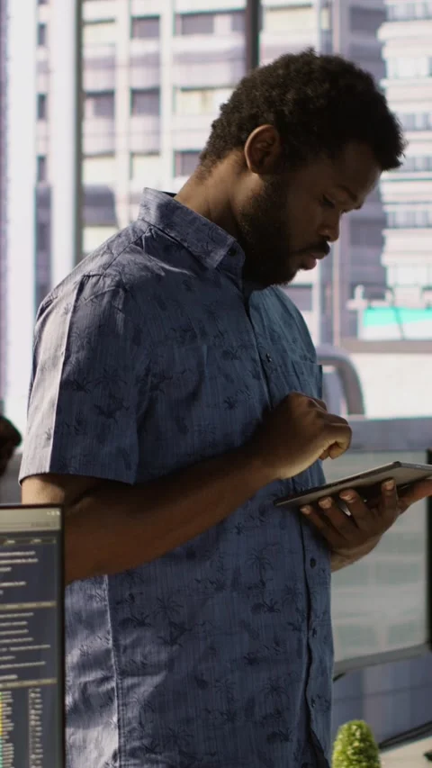 Vertical video Man walking with tablet in office, fixing coding issues Stock Footage 319488662