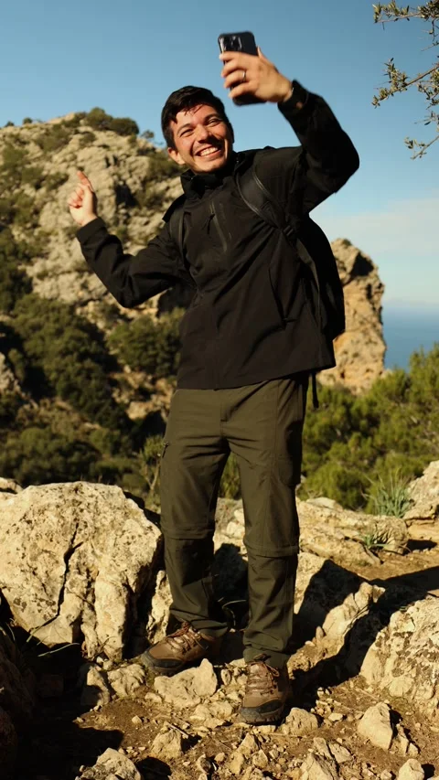 Vertical video of a man walking on top of a mountain taking a selfie with h.. Stock Footage 296380581