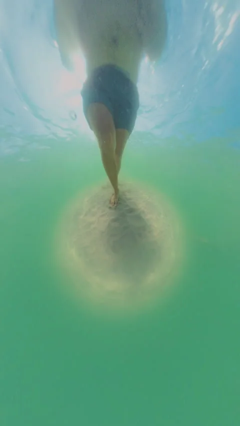 Vertical video. Man Walking Underwater On Sandy Bottom, Feet Stirring Sand Cloud Stock Footage 333270699