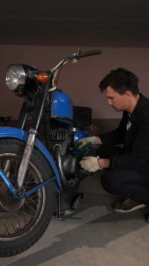 Vertical video man wearing work gloves concentrating on restoring an old blue Stock Footage 342773157