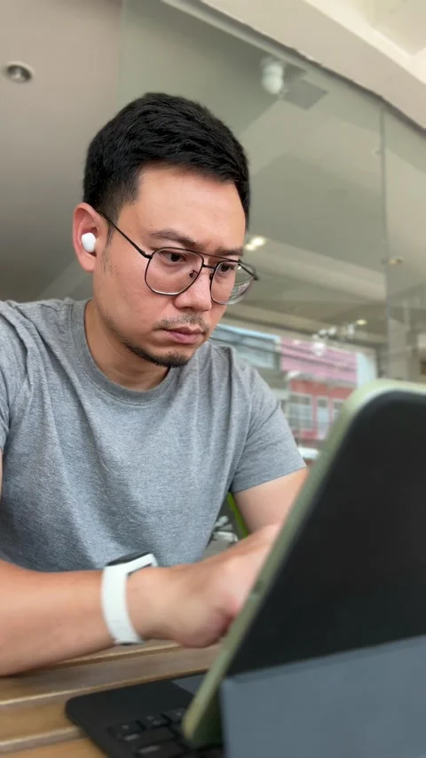 Vertical video of man working with his tablet computer in the cafe. Stock Footage 266994351
