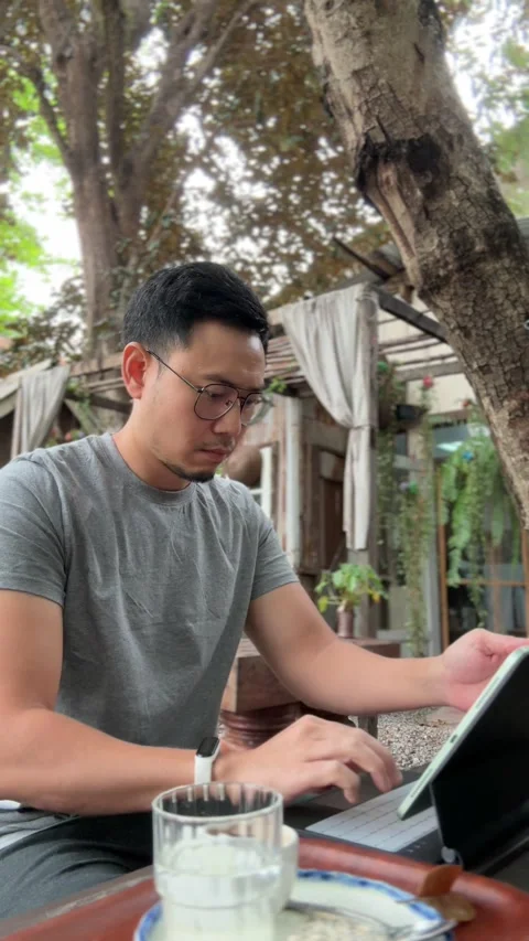 Vertical video of man working on his tablet computer and drinking coffee. Stock Footage 266994360