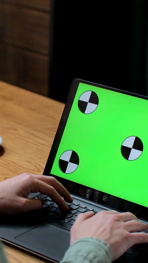 Vertical video. Man working on laptop with green screen in coffee shop. Video stock 345235993