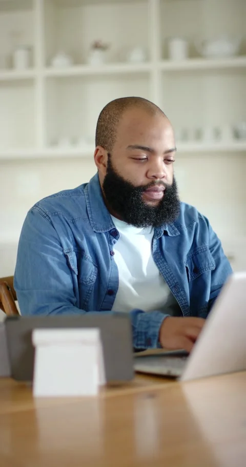 Vertical video: Man working at table typing on laptop, pausing, resuming as tech Stock Footage 346724217