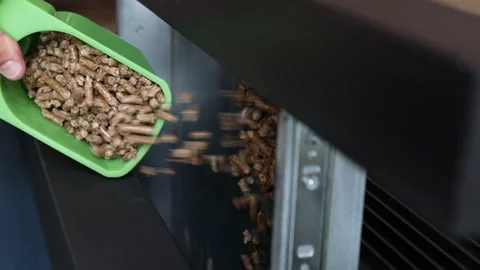 Vertical video of man's hand pouring pellets into a fireplace. Energy saving. Stock Footage 220013342