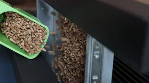Vertical video of man's hand pouring wood pellets into a fireplace. Video stock 221754683