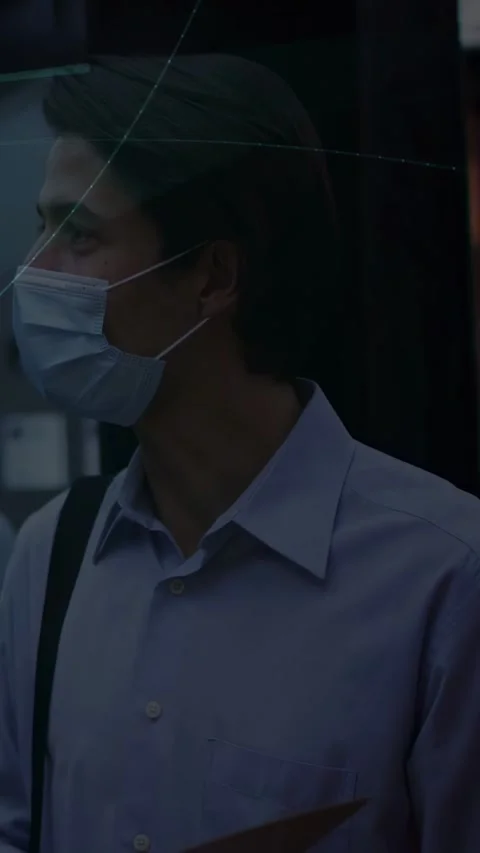 Vertical video: Masked man turning head starting blue tech overlays showing data Stock Footage 333157488