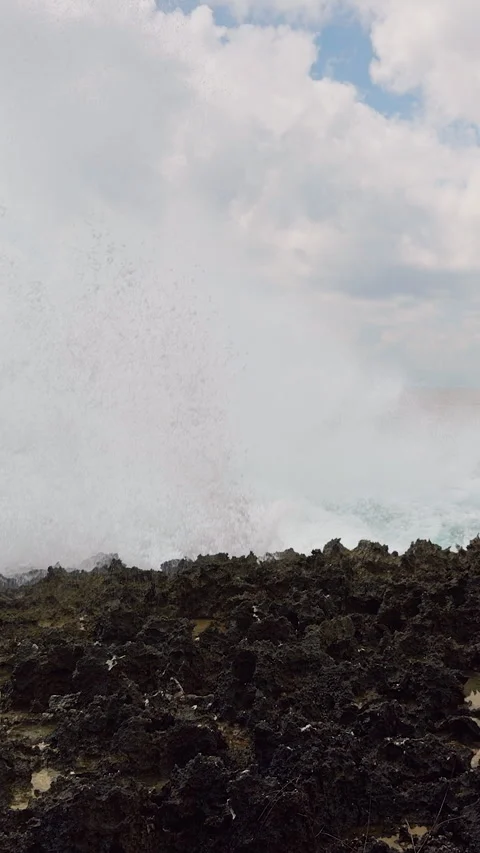 Vertical video. Massive Ocean Wave Exploding Across Jagged Coastal Rocks in Dram Stock Footage 337061765
