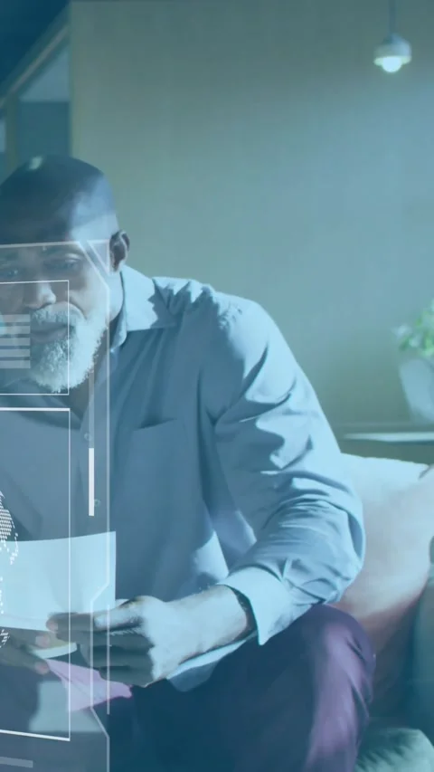 Vertical video: Mature man on sofa holding paper, reviewing tech hologram charts Stock Footage 330982542