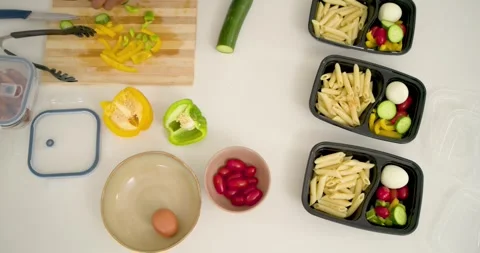 Vertical video: Meal prepping hands reaching slicing cucumber placing pasta veg Stock Footage 344318292