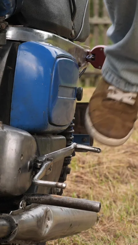 Vertical video Mechanic starting old motorcycle engine with kick starter Video stock 314952010