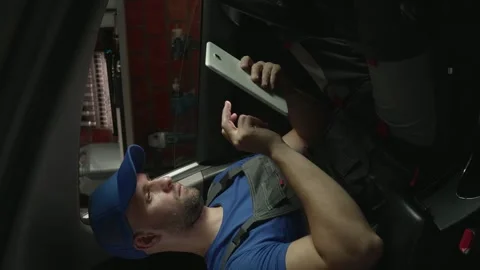Vertical video: A mechanic studies the diagnostic results on a tablet while Stock Footage 280378520