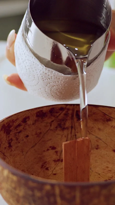 Vertical video. Melted Wax Stream Pouring Directly into Coconut Shell with Woode Stock Footage 323989125