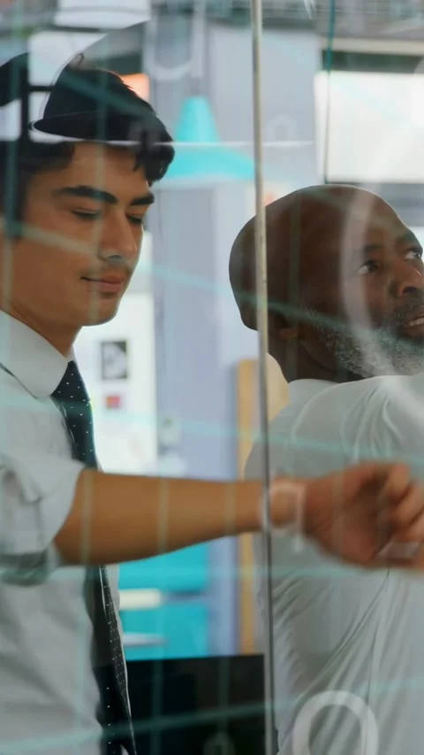 Vertical video: Mentee pointing, mentor guiding, animated charts on glass aiding Stock Footage 333110095