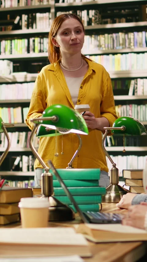 Vertical Video Mentor at group study speaking with peers seated at library table Stock Footage 336378750