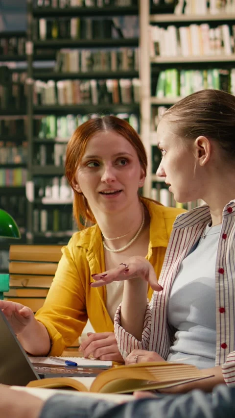 Vertical Video Mentor guiding student through academic work on laptop at library Stock Footage 336379184