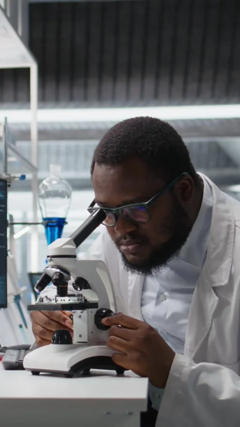 Vertical video Microbiologist in lab inspects slide using optical device Stock Footage 319722204