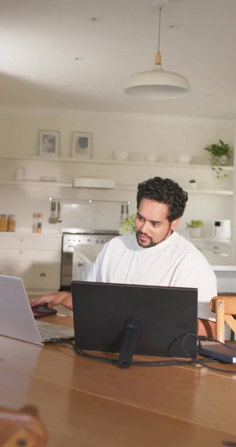 Vertical video: Mid 30s African man checking red phone before working on dual Stock Footage 345131048