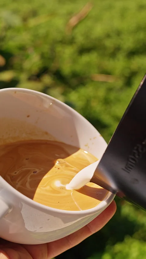 Vertical video. Milk Pouring Into Fresh Coffee Creating Latte Art Pattern in Whi Stock Footage 330133626