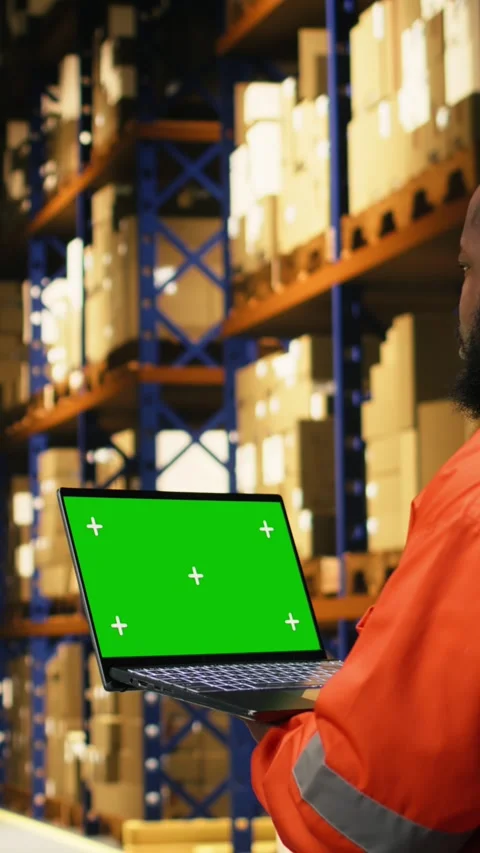 Vertical Video Mockup screen on laptop in industrial warehouse with black worker Stock Footage 333090082