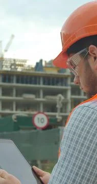 Vertical video. Modern construction engineer or architect in helmet at constr Stock Photos