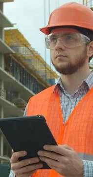 Vertical video. Modern construction engineer or architect in helmet at constr Stock Photos