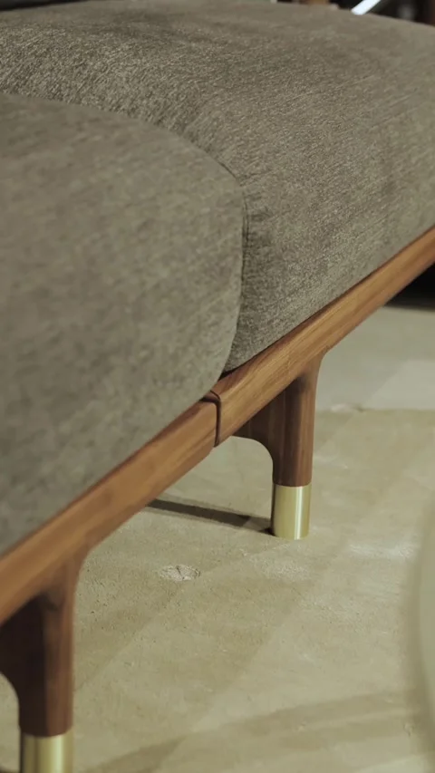 Vertical video. A modern sofa, with gray frame and wooden legs and gold elements Stock Footage 322529182