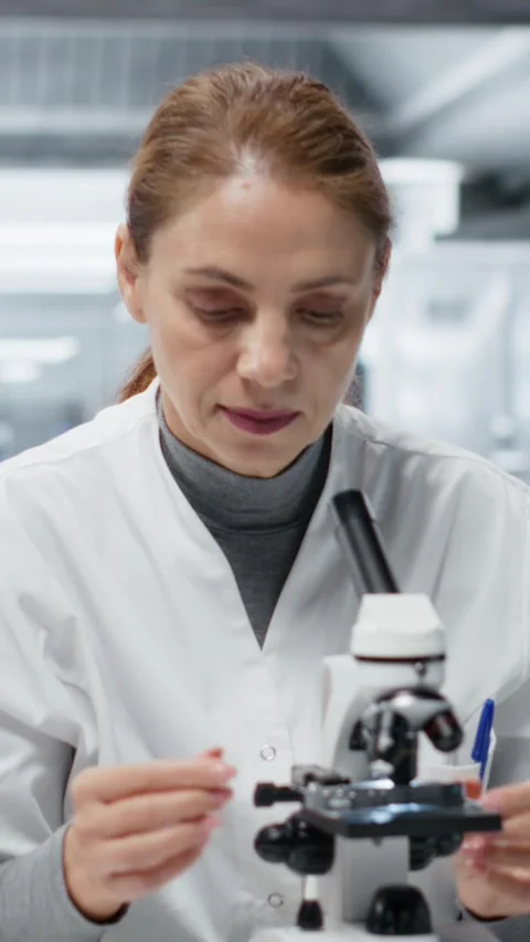 Vertical video Molecular biologist using compound microscope for detailed Stock Footage 325681014