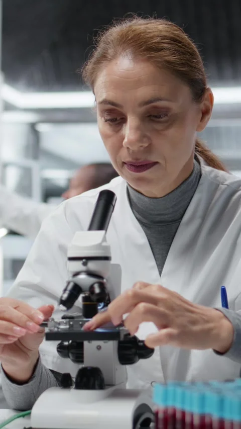 Vertical video Molecular biologist using compound microscope for detailed Stock Footage 325916883