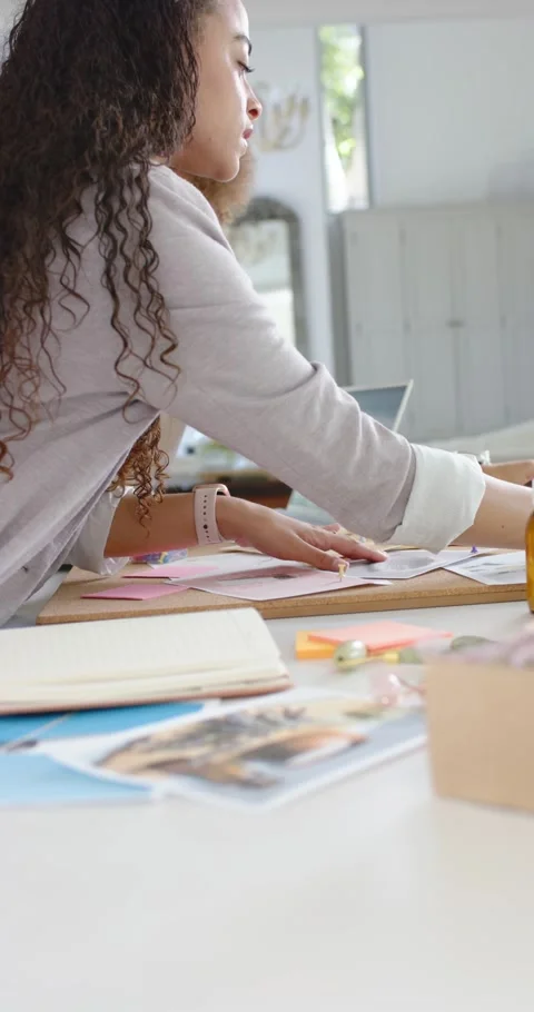 Vertical video: Mom and kid are sorting prints bottles and pens on table after Stock Footage 345396202